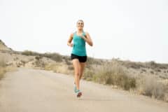 [:he]A woman is running in the desert, wearing a turquoise tunic and dark pants, in a quiet and open landscape.[:]