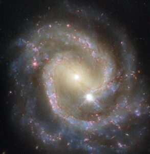 Spiral galaxy NGC 7469 in Phis, bright core, colorful star arms, star formation.