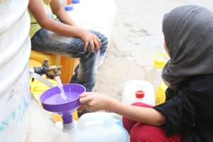 أطفال في طهران يملؤون أباريق من خزان مياه عام. التُقطت الصورة عام ٢٠٢٠. المصدر: depositphotos.com