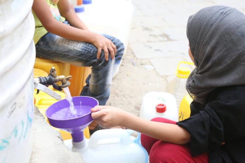 ילדים בטהרן ממלאים כדים ממכל מים ציבורי. התמונה צולמה בשנת 2020.  <a href="https://depositphotos.com. ">המחשה: depositphotos.com</a>