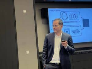 البروفيسور كريستيان ماير يعرض حاسوبًا عصبيًا متعدد الوحدات في مؤتمر TSMC بأمستردام. تصوير: آفي بيليزوفسكي